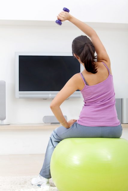 Woman exercising at home in front of the tv